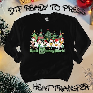 May include: Black sweatshirt with a Christmas-themed design featuring Mickey Mouse, Donald Duck, Goofy, and Pluto in front of Christmas trees. The text "Walt Disney World" is printed below the characters.