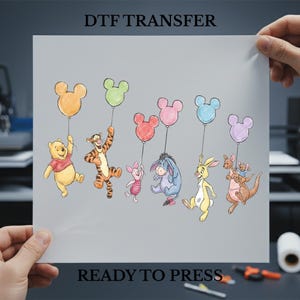 May include: A DTF transfer sheet featuring a colorful illustration of Winnie the Pooh and friends holding Mickey Mouse-shaped balloons. The text "DTF TRANSFER" and "READY TO PRESS" are printed on the sheet.