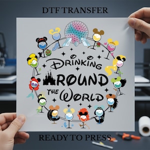 May include: A DTF transfer featuring the text "Drinking Round the World" with cartoon characters in wine glasses. The design includes a castle, a globe, and the words "Ready to Press."