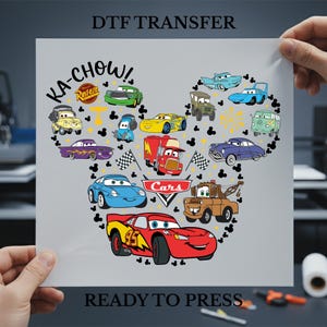 May include: A gray DTF transfer sheet featuring a collection of cartoon cars arranged in a Mickey Mouse head shape. The design includes the text "Ka-Chow!" and "Cars", along with various car characters in vibrant colors. The words "Ready to Press" are at the bottom.