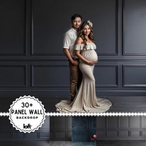 May include: A couple poses in front of a dark gray panel wall backdrop. The woman wears a beige off-the-shoulder maternity gown. The man wears a white shirt and brown pants. The backdrop has the text "30+ PANEL WALL BACKDROP" and the brand "loft".