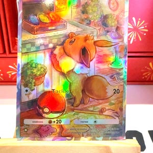 Könnte beinhalten: Holografische Pokémon-Sammelkarte mit einem Evoli-Charakter. Die Karte hat ein farbenfrohes, schillerndes Design mit dem Wort "Tackle" und der Zahl "20". Die Karte enthält auch den Text "Its ability to evolve into many forms allows it to adapt smoothly and perfectly to any environment."