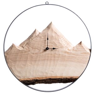 Könnte beinhalten: Eine Wanduhr aus Holz in Form eines Gebirges, mit schwarzen Zeigern und einem Metallring am Rand.