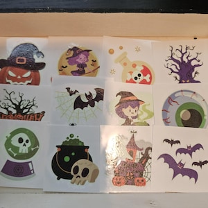 May include: A collection of twelve square temporary tattoos featuring Halloween themes including a jack-o'-lantern, a witch, a potion bottle, a skull, a haunted house, bats, a spider web, a green eyeball, and a crystal ball with a skull.