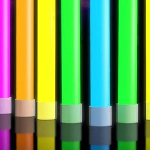 May include: A row of seven cylindrical glow sticks in vibrant colors including pink, orange, yellow, green, and blue. Each stick features a light gray plastic cap with a circular hole at the top and a matching base, standing upright in a line.