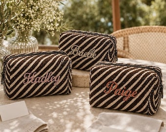 Könnte beinhalten: Drei rechteckige Reißverschlusstaschen mit einem diagonalen Streifenmuster in Dunkelbraun und Creme. Jede Tasche ist mit einem Namen in Schreibschrift bestickt: Brielle, Hadley und Paige. Die Taschen haben eine strukturierte Weboptik.
