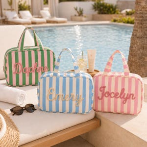 May include: Three rectangular travel bags with top handles and vertical stripes. The green and pink bag features the name Daphne, the blue and white bag features the name Emery, and the pink and white bag features the name Jocelyn in script.