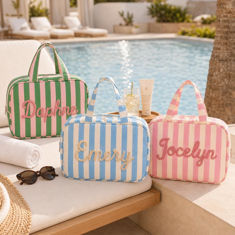 May include: Three rectangular travel bags with top handles and vertical stripes. The green and pink bag features the name Daphne, the blue and white bag features the name Emery, and the pink and white bag features the name Jocelyn in script.