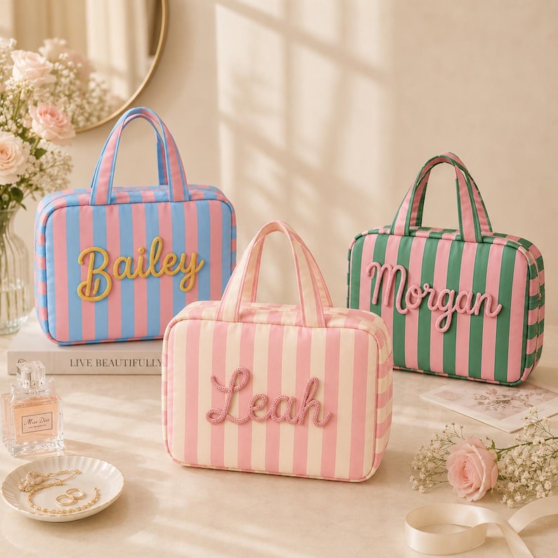 May include: Three rectangular striped travel bags with top handles. One bag is blue and pink with the name Bailey, one is pink and white with the name Leah, and one is green and pink with the name Morgan. Each bag features raised lettering.