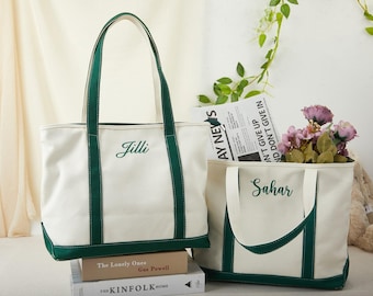 May include: Two white canvas tote bags with green accents. One bag has "Jilli" embroidered on it, the other has "Sahar". The bags have green handles and bases. One bag contains flowers and a newspaper.