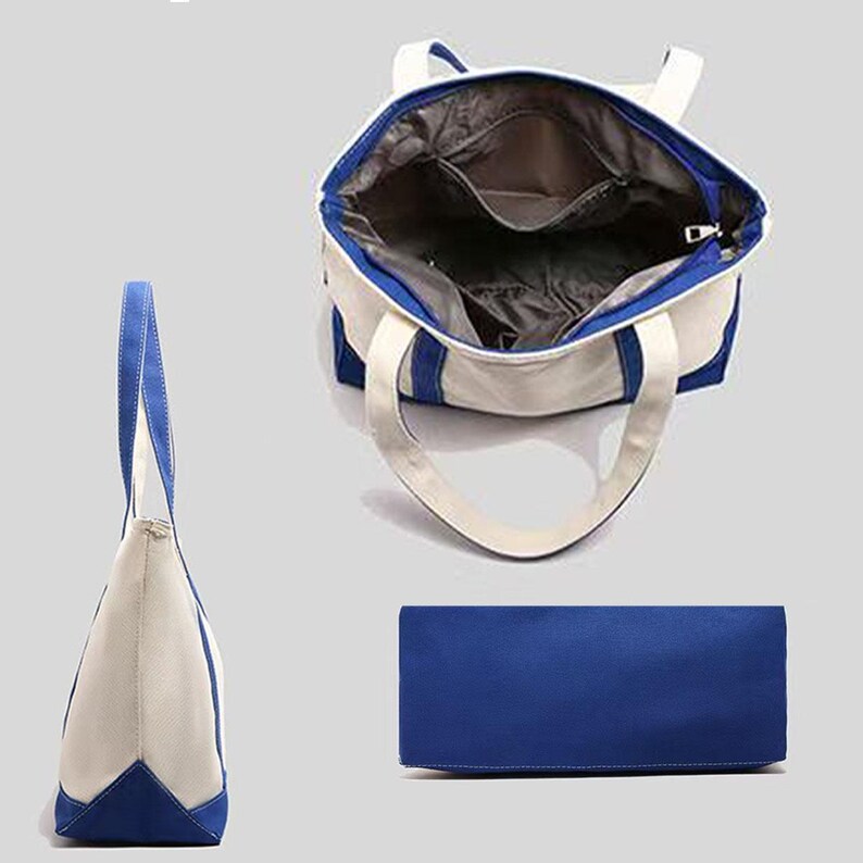 May include: A canvas tote bag in three views: side, top-down, and bottom. The bag is mainly off-white with blue accents on the handles, trim, and base. The interior is grey. The bag has a zip closure and two handles.