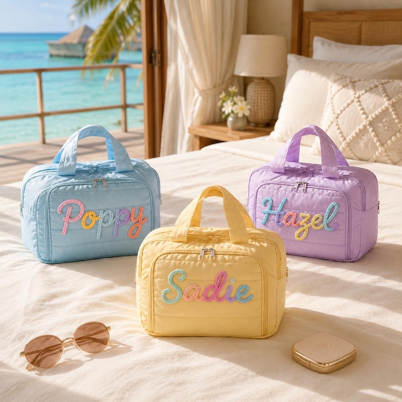 Puede incluir: Tres bolsas de viaje acolchadas rectangulares en azul claro, amarillo y lavanda. Cada bolsa cuenta con dos asas superiores, un cierre de cremallera y un nombre bordado de colores en la parte frontal que dice Poppy, Sadie o Hazel en cursiva.