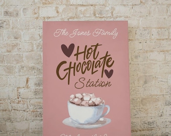 May include: A pink sign with the text "The Jones Family Hot Chocolate Station" in brown lettering. The sign also features a white cup of hot chocolate with marshmallows and the text "Made with Love" in brown lettering.