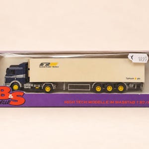 Könnte beinhalten: Ein 1:87 Modell-Sattelzug in einer violetten B&S Modelle Schachtel. Der LKW hat ein dunkelblaues Fahrerhaus und einen cremefarbenen Auflieger mit der Aufschrift Central Trailer Rentco und Tiphook plc. Die Räder sind gelb und die Schachtel trägt den Text High Tech Modelle im Masstab 1:87/HO.