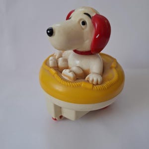 Heel schattig klein vintage blauw opwindbaar hondenspeelgoed in geel reddingsvlot - ziet eruit als snoopy :)