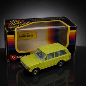 May include: A lime green diecast metal model Range Rover, presented in its original box. The box is labelled "1/43 Diecast Metal Model" and "Range Rover". The box has a black background with a yellow and rainbow stripe design.