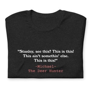 Könnte beinhalten: Ein schwarzes T-Shirt mit einem weißen Zitat aus dem Film "Die Hirschjagd" mit dem Text: "Stanley, siehst du das? Das ist das! Das ist nicht etwas anderes. Das ist das!" -Michael- Der Hirschjäger.
