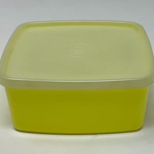 May include: A yellow plastic rectangular container with a white lid. The container has a smooth surface and rounded edges.