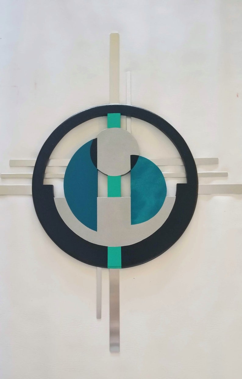 May include: A wall art piece featuring a large black circular frame with horizontal and vertical silver bars extending outward. Inside the circle are two teal semi-circular shapes, a central silver disc, and a vertical teal stripe running through the center.