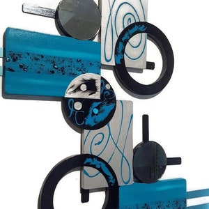 May include: Abstract wall art featuring geometric shapes in black, silver, and turquoise blue. The piece includes circles, squares, and rectangles with a modern design.