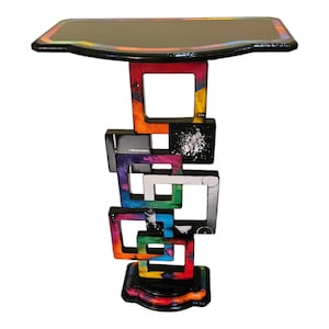 May include: A colorful side table with a black top and a base made of stacked, painted squares. The squares are painted in various colors, including red, orange, yellow, green, blue, purple, and black.