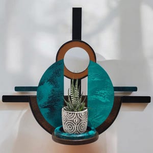May include: A teal and brown geometric wall shelf with a small potted succulent plant. The shelf has a circular design with a cutout in the center.