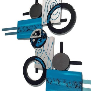 May include: Abstract wall art sculpture with geometric shapes in black, silver, and turquoise blue. The sculpture features circles, squares, and rectangles with a swirling design.