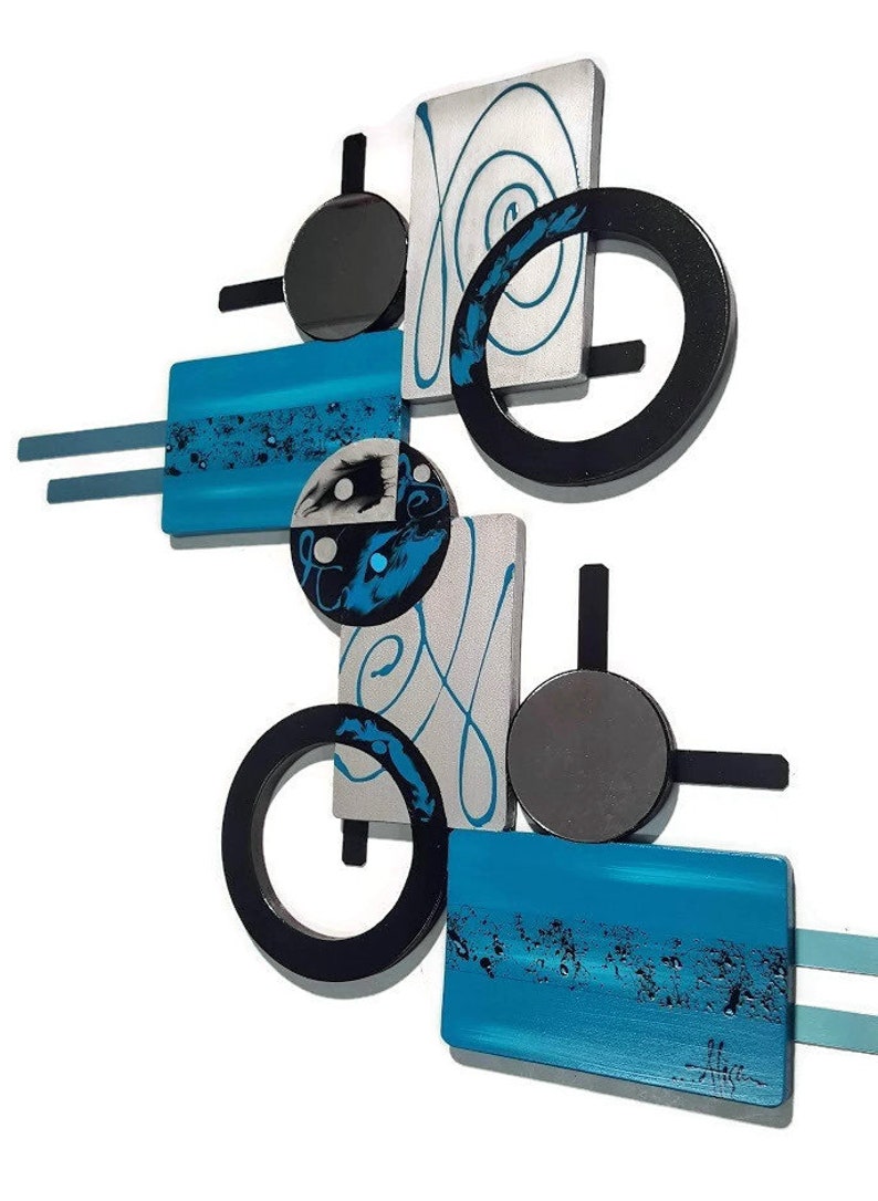 May include: Abstract wall art sculpture with geometric shapes in black, silver, and turquoise blue. The sculpture features circles, squares, and rectangles with a swirling design.