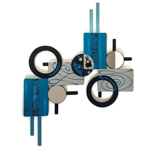 May include: Abstract wall art featuring geometric shapes in shades of blue, black, and silver. The piece includes circles, squares, and rectangles, with a swirling pattern on some of the shapes.