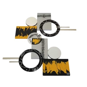 May include: Abstract wall art sculpture with geometric shapes in black, white, and yellow. The sculpture features circles, squares, and rectangles.