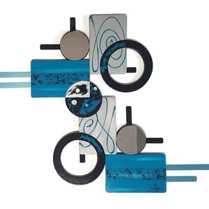 May include: Abstract wall art sculpture with geometric shapes in shades of blue, black, silver, and white. The sculpture features circles, squares, and rectangles.