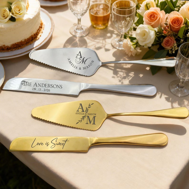 May include: Four wedding cake serving utensils on a table. Two silver utensils are engraved with "AMELIA & MASON" and "THE ANDERSONS 09.13.2026". Two gold utensils are engraved with "A AMELIA & MASON M" and "Love is Sweet".