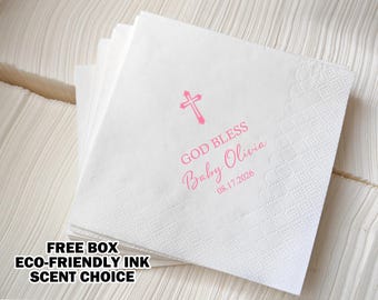 May include: White paper napkins with a pink cross, the text "God Bless Baby Olivia 08.17.2026" and a decorative border.