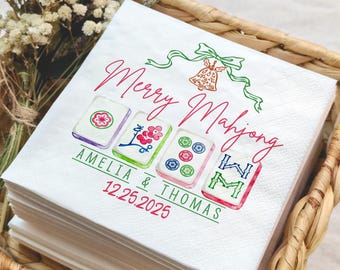 May include: White paper napkins with a "Merry Mahjong" design in red and green script. The napkins feature four illustrated Mahjong tiles and the names "Amelia & Thomas" with the date "12.25.2025".