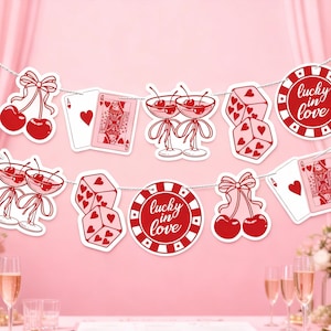 Puede incluir: Una pancarta festiva con recortes temáticos de casino en rojo y blanco. El diseño incluye cerezas, naipes, dados y fichas de casino con el texto "lucky in love". El fondo es de color rosa suave.