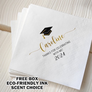 May include: White graduation napkins with gold script text that reads "Caroline, Thanks for Celebrating with Me! 2024" and a black and gold graduation cap graphic. The napkins are stacked and ready for a graduation party.