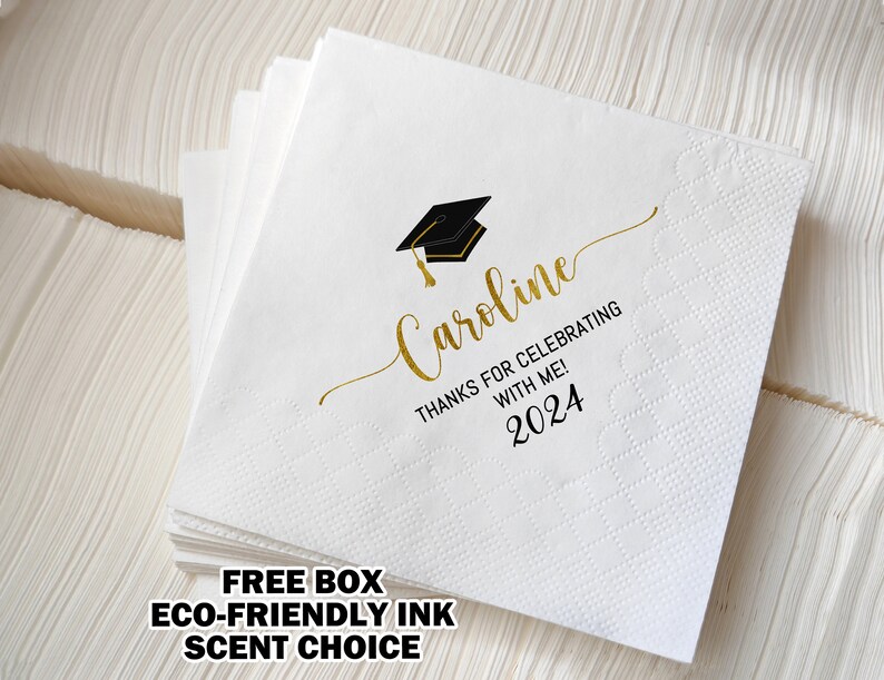 May include: White graduation napkins with gold script text that reads "Caroline, Thanks for Celebrating with Me! 2024" and a black and gold graduation cap graphic. The napkins are stacked and ready for a graduation party.