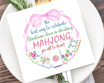 May include: Square white paper napkin with a watercolor design. The napkin features a pink bow and the text "The best way to celebrate Christmas cheer is shouting MAHJONG for all to hear!" with Mahjong tiles.