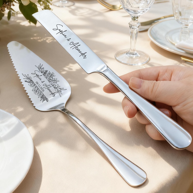 May include: A silver cake knife and server set. The knife and server are engraved with the names "Sophia & Alexander" and the date "08.12.2026". The server has a floral design.