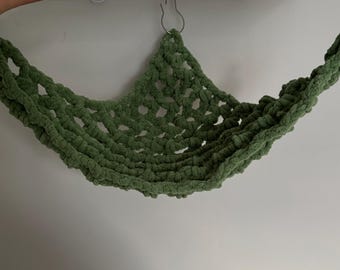Puede incluir: Una hamaca de crochet verde para mascotas pequeñas, colgada de dos ganchos metálicos.