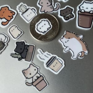 Puede incluir: Una colecci&oacute;n de pegatinas con tem&aacute;tica de gatos, que representan gatos de dibujos animados en varias poses. Las pegatinas muestran gatos en macetas, con hilo y otros dise&ntilde;os l&uacute;dicos. Se incluye una moneda para referencia de tama&ntilde;o. Las pegatinas son coloridas y tienen un acabado brillante.