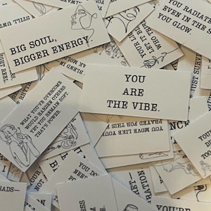 May include: A collection of small, rectangular cards with various inspirational quotes and line art illustrations in black ink. The cards are primarily white with black text, featuring phrases like "Big Soul, Bigger Energy" and "You Are The Vibe."