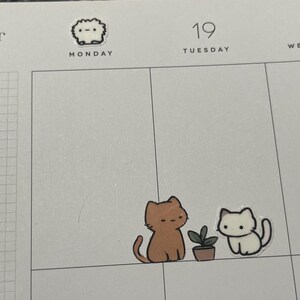 Puede incluir: Una p&aacute;gina de planificador con pegatinas con tem&aacute;tica de gatos. Una pegatina dice "Yee Haw!". Dos pegatinas de gatos est&aacute;n cerca de una peque&ntilde;a planta en maceta. La p&aacute;gina est&aacute; marcada para el 19 y 20 de noviembre.