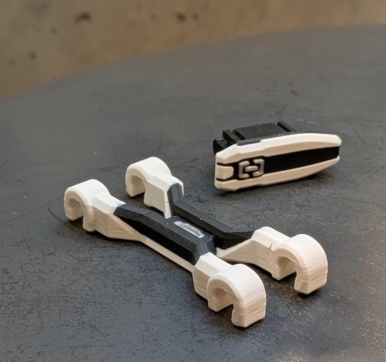 May include: A set of 3D-printed white and black plastic components. Two larger pieces have a curved design with a central black section. A smaller, rectangular piece with a black stripe and a central design is also present.