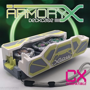 Puede incluir: Una caja de plástico blanca y amarilla con un interior gris. La caja está abierta y tiene tres peonzas dentro. La caja tiene las palabras "Armory X Deckcase" en la parte delantera. La caja es compatible con DX.