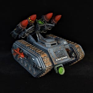 Könnte beinhalten: Detailliertes Modell eines Militärpanzers in Dunkelgrau und Braun. Er hat rote Raketen, ein grünes Zielsystem und den Text "In Death Redemption". Der Panzer hat die Nummer "212" an der Seite.