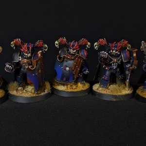 May include: Five blue and red painted miniature figures with swords and shields. The figures are standing on circular bases.