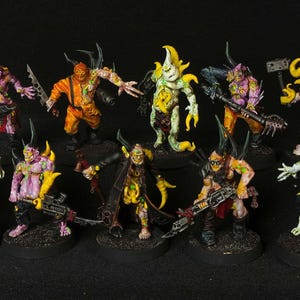 May include: A collection of 10 painted miniature figures, each with a unique design and color scheme. The figures are posed in a variety of dynamic stances, and they are all holding weapons or tools. The figures are made of plastic and are painted in a variety of colors, including green, yellow, orange, pink, and white.