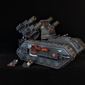 Könnte beinhalten: Detailliertes Modell eines Militärpanzers in Grau- und Schwarztönen mit mehreren Raketenwerfern und aufwendigen Details. Der Panzer hat eine rote Raketengrafik und die Nummer "215" an der Seite.