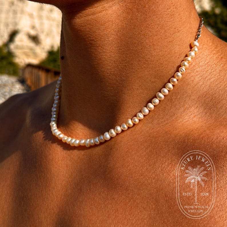 May include: A delicate pearl necklace with a silver clasp. The necklace is composed of small, round, off-white pearls. The necklace is a jewelry item.